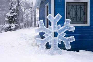 LED snowflake figure in the snow  by the wall of a building at a ski resort.