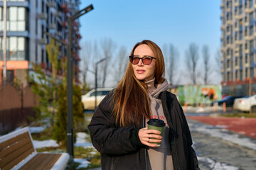 Fototapeta premium girl walks down the street with coffee in the spring
