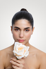 Beauty portrait featuring a woman holding a rose against a neutral background