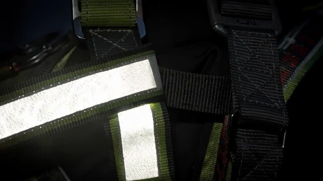 Medium frame showcasing reflective safety harness webbing glowing under low light ensuring maximum visibility and protection for nighttime climbing and rescue operations.