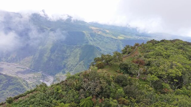 Drone orbit shot around hikers at a scenic viewpoint, overlooking lush tropical mountains and deep valleys, people admiring the landscape at Sentier Botanique Notre-Dame de la Paix, Reunion Island.