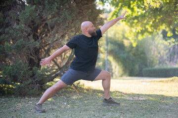 Outdoor Stretching Exercise in Green Park. Healthy Lifestyle Concept with Man Stretching Outside. Man Stretching in the Park. Man Warming Up with Stretching Exercises Outdoors.