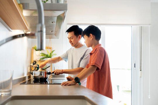 Chinese father and son cooking together in kitchen