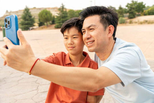Father and son taking selfie in park