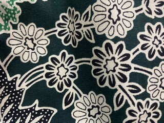Fototapeta premium Close-up view of a dark green fabric with a white floral pattern, showcasing intricate details of blooming flowers and leaves