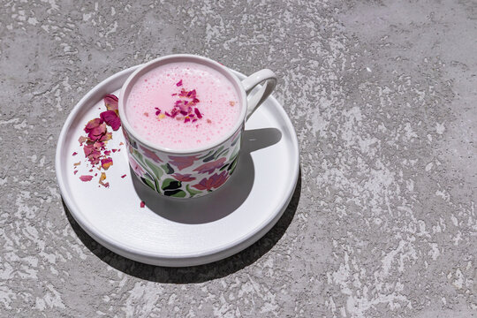 Pink matcha latte with floral garnish on white saucer