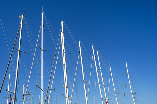Row of yacht masts against a clear blue sky