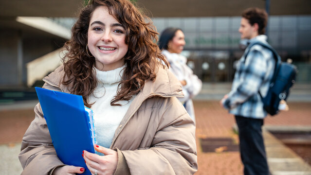 Student holding folders on vibrant university campus