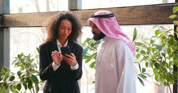 Handsome muslim man businessman wearing stylish keffiyeh and beautiful woman holding mobile phone
