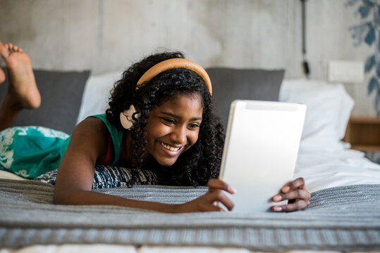 Young girl enjoying tablet time in bed