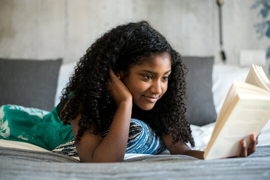 Teenage girl enjoys reading book in cozy bed setting