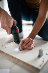 Person assembling flat pack furniture using electric screwdriver
