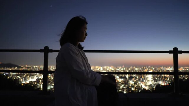 Silhouette Woman Contemplating City Lights at Dusk.