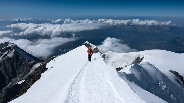An LHO alpine climber on the Mont Blanc summit ridge with a sweeping panorama of the French Alps behind, capturing exposure, achievement, and classic high altitude mountaineering.