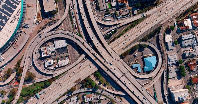 Famous interchange of Los Angeles, California, USA at daytime. Lots of cars run by the loops, highways and trestles. Top view.