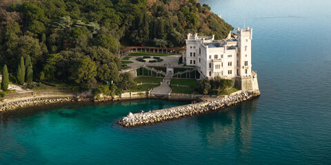 Aerial view of Miramare Castle on the cliff with white stone architecture and seaside garden at sunset Gulf of Trieste Italy High Resolution