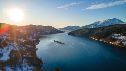 Obraz premium Vista aerea de hermoso lugar con nieve y fiordos en noruega. Aerial view of mirror-like waters reflecting snow-dusted mountains under a muted sky, creating a serene and majestic winter tableau.