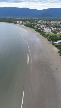 Vista a&eacute;rea da Praia do Indai&aacute;, no litoral de Bertioga, evidenciando a paisagem natural, a linha da costa e o contraste entre mar e cidade.