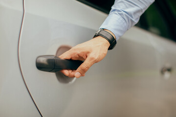 Unrecognizable man hand with expensive watch on opening luxury car back door, closeup photo. Businessman getting inside the auto, cropped of driver assisting manager, open automobile door © Prostock-studio