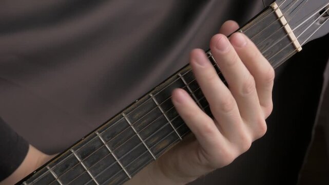 Close-up of hand pressing guitar strings on acoustic guitar neck, showing finger placement and technique progression. close up professional guitar acoustic