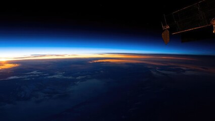 Fototapeta premium Sunrise over Earth from space, thin blue atmosphere along the horizon, with part of a satellite/space station visible on the right. Concept Space Dawn over Earth, Thin blue atmospheric halo