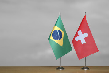 Table flags of Brazil and Switzerland on gray blurred background