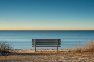 Quiet bench overlooking calm waters at sunrise near sandy beach