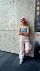 A portrait of a teenage girl with red hair posing for a photo near columns at the entrance to a business center