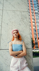 A portrait of a teenage girl with red hair posing for a photo near columns at the entrance to a business center
