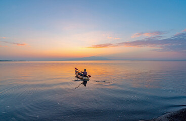 Fototapeta premium A kayaker paddling in the ocean of Hawaii at sunrise