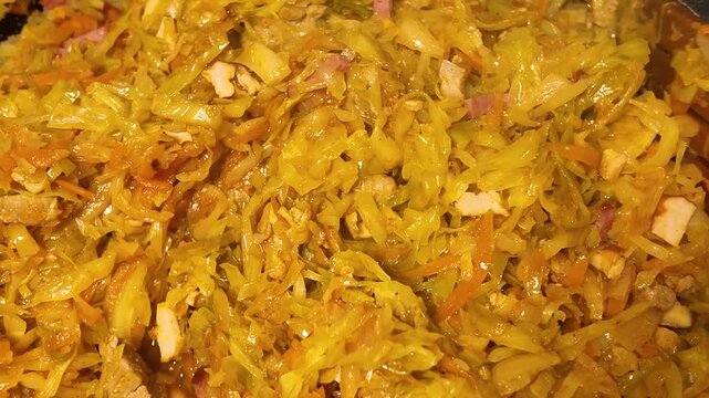 Preparing of traditional dish bigos with sausage, meat, carrot and cabbage on a frying pan, stewed cabbage. 