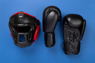 Fototapeta premium Boxing helmet and gloves on color background, top view.