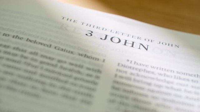 Bible pages flipping to 3 John letter book. Turning pages of the New Testament letter regarding hospitality, truth, and faithful service. 4K close up shot for religious study and scripture.