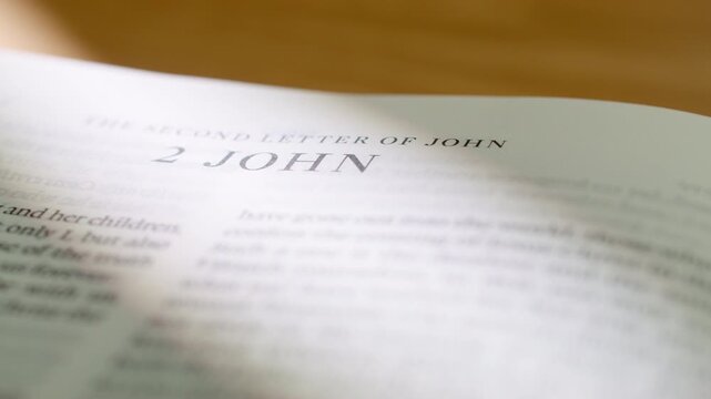 Bible pages flipping to 2 John letter book. Turning pages of the New Testament letter regarding walking in truth and the commandment of love. 4K close up shot for religious study and scripture.