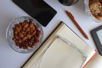 Notebook, pen, tablet, phone, coffee and snacks on white background. Top view.