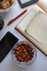 Notebook, pen, tablet, phone, coffee and snacks on white background. Top view.