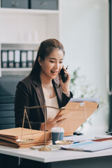 Confident Lawyer Working at Desk: A young Asian female lawyer confidently works on her laptop,...