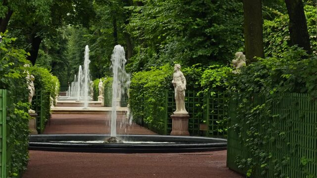 fountain gallery in the summer garden in St. Petersburg, Russia, white statues on pedestals, bright green trees around, no people