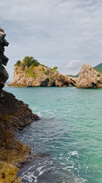 Montenegro, picturesque scenery of seaside promenade on a sunny day, moored boats, brick-colored tiled roofs, a mountain range in the background