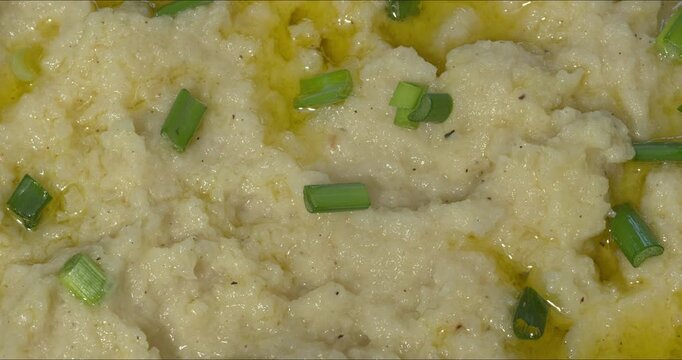 Close-up of the texture of Turnip Skordalia. Creamy Greek dip made of turnips, garlic, and olive oil garnished with chopped scallions and olive oil. 