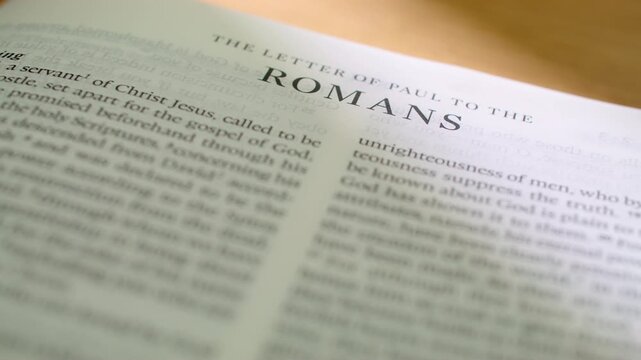 Romans Bible book pages turn during a close up study of holy scripture. A high-quality shot of flipping through the pages of the Epistle to the Romans regarding faith, grace, and salvation.