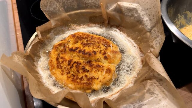 Meat being fried in a frying pan. Top view. Breaded meat in bubbling oil. Homemade dinner.