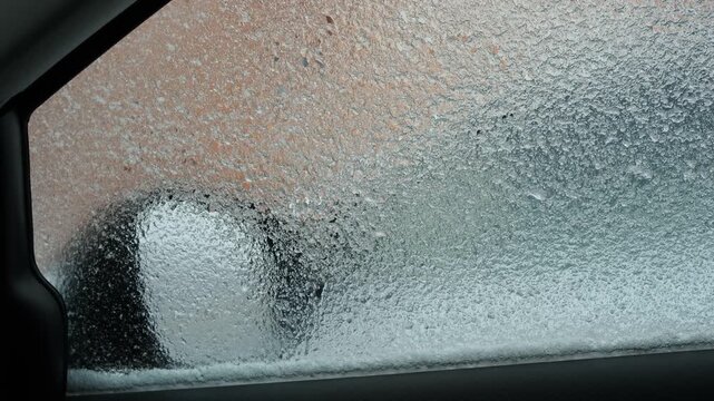 A view from inside a frozen car, showing the warm air defroster system in operation in winter