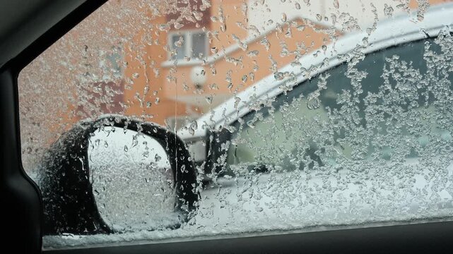A view from inside a frozen car showing the warm air windshield defrost system in operation during winter.