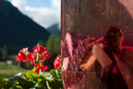 Close-up of Swiss stone pine cone infusion in glass jar, homemade Tyrolean Zirbala schnapps in sunlight with alpine bokeh