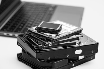 Stacks of various hard drives and a laptop for data storage and archiving.  Laptop Surrounded by Multiple Hard Drives for Archiving Data