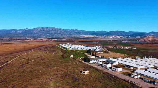 Aerial agricultural complex and fields. Drone view of agricultural farm buildings with fields and mountains in background