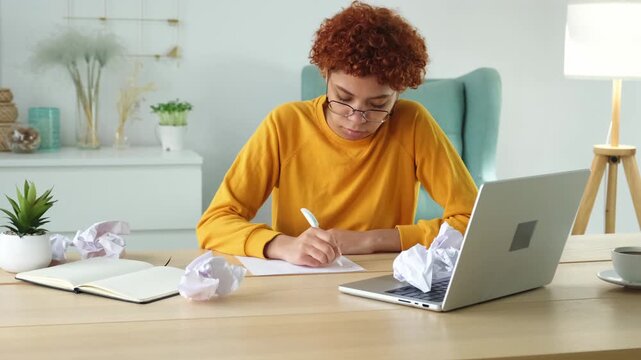 Serious african woman with crumpled paper having problem writing by hand document studying learning at home. Girl no idea sitting at workplace writing notes at office. Start up business deadline