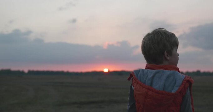Boy Enjoy Nature. Kid Watch Sunset Sky over Field. 4K 10-bit