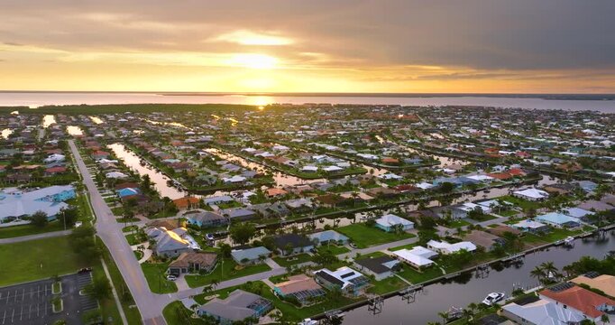 Wealthy waterfront neighborhood in southern Florida at sunset. Expensive houses surrounded by palm trees and reflecting evening glow.
